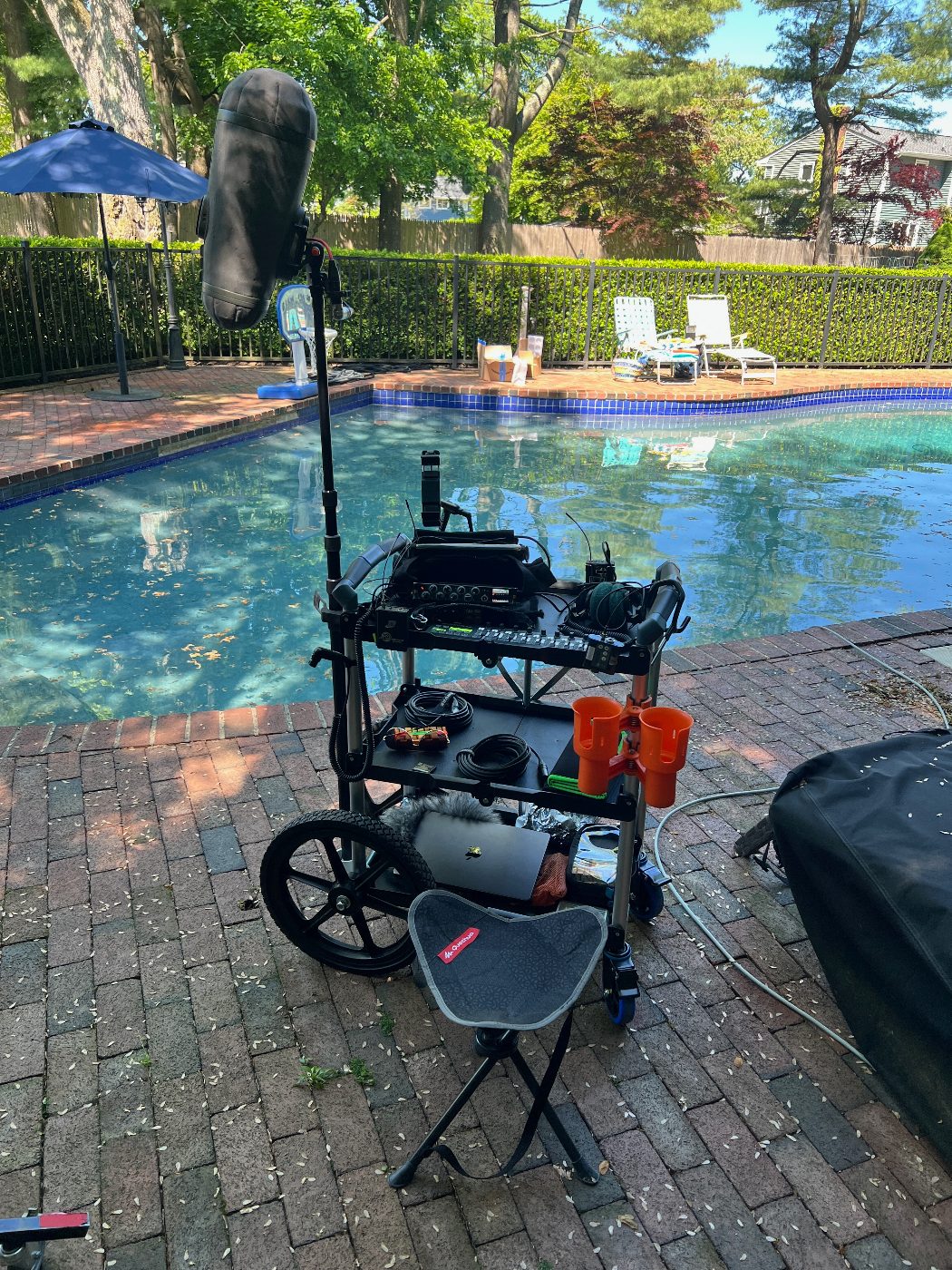 Sound cart with Sound Devices mixer, Lectrosonics wireless, and a blimped boom microphone set up poolside on a location shoot outside New York City